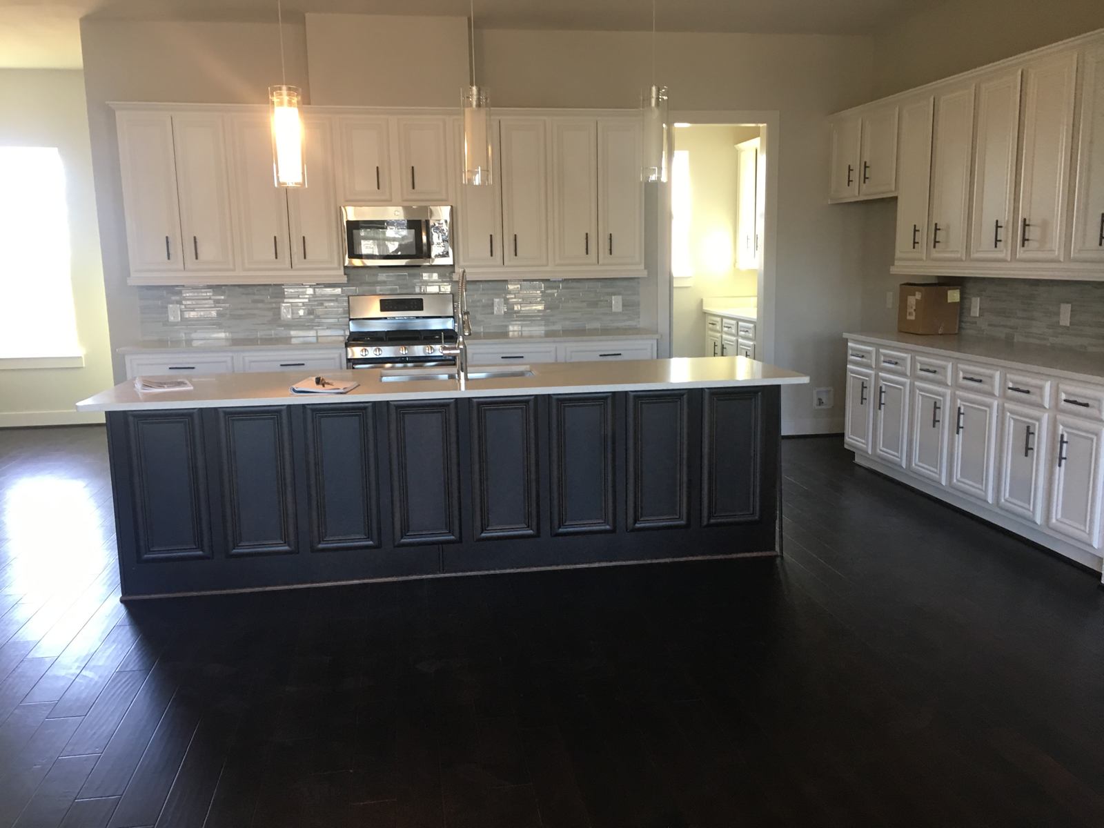 A new kitchen with white cabinets, a navy island and dark wood floors after a final clean